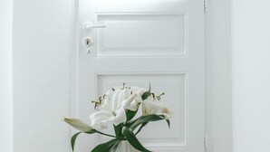 A white door with a white vase of white flowers on a small round table. - Roofs of Chora, Townhouse with Rooftop Pool - Adults Only (Mykonos)