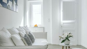 A minimalist white room with a bed, a small round table, and a window with a view. - Roofs of Chora, Townhouse with Rooftop Pool - Adults Only (Mykonos)