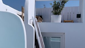 A white infinity pool with clear blue water, a ladder leading to a door, and a potted plant on the balcony. - Roofs of Chora, Townhouse with Rooftop Pool - Adults Only (Mykonos)