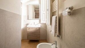 Een moderne badkamer met een houten wastafelmeubel, een witte wasbak, een spiegel en een handdoekrek.