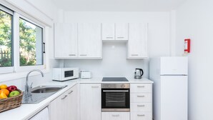 Eine moderne Küche mit weißen Schränken, einer Edelstahl-Spüle, einer Mikrowelle, einem Herd und einem Kühlschrank.