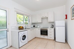 Eine kleine Küche mit Waschmaschine, Mikrowelle, Backofen und Kühlschrank.