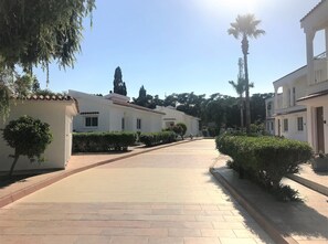 Ein gepflasterter Weg führt zu einem weißen Gebäude mit zahlreichen Fenstern und einem Ziegeldach.