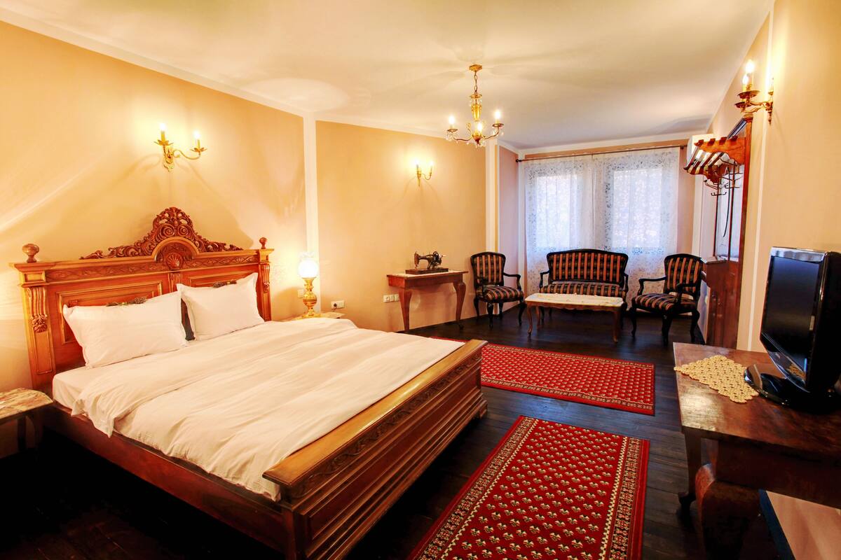 A hotel room with a large bed, a television, a desk, and two chairs.