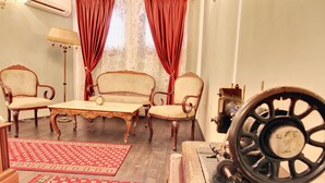 A room with a vintage table, four chairs, a rotary phone, and patterned rugs.