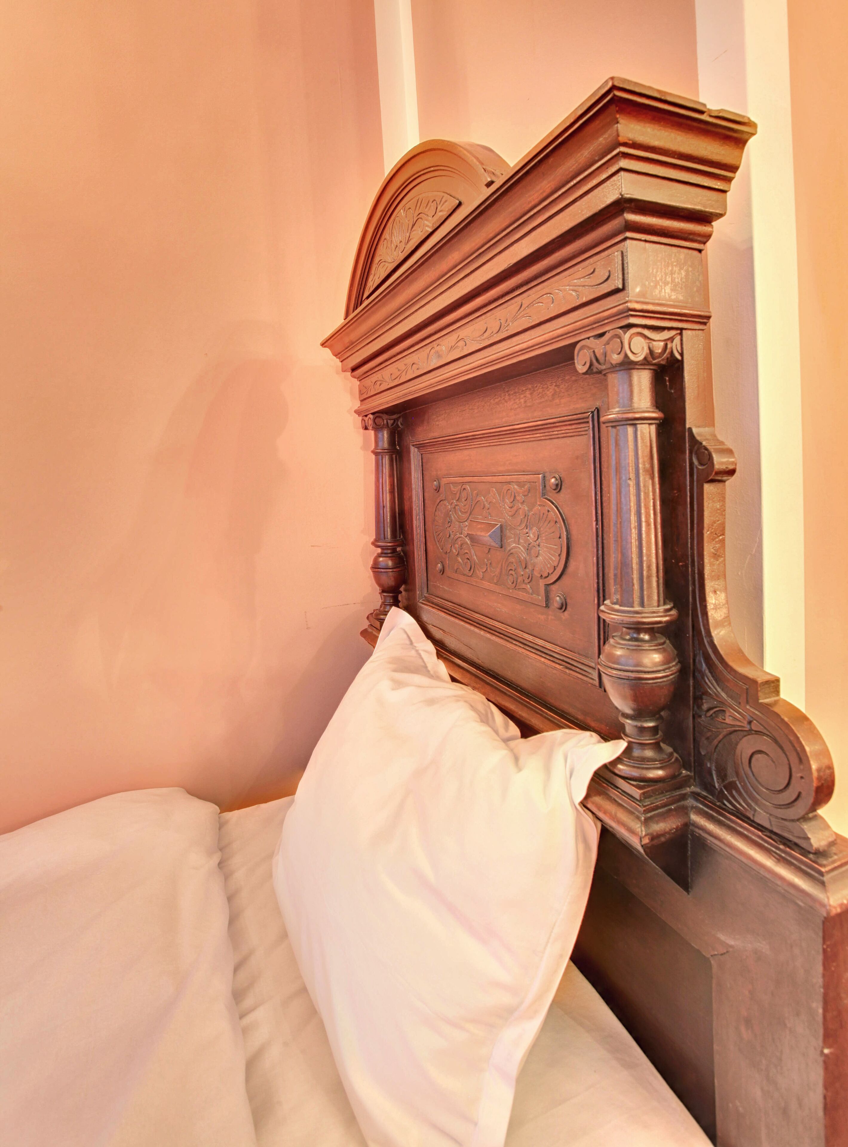 A bed with a wooden headboard and a white pillow.