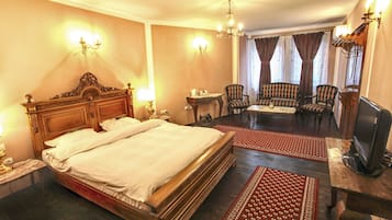 Une chambre d’hôtel dotée d’un grand lit, d’une télévision, d’un bureau et d’un coin salon avec des fauteuils.