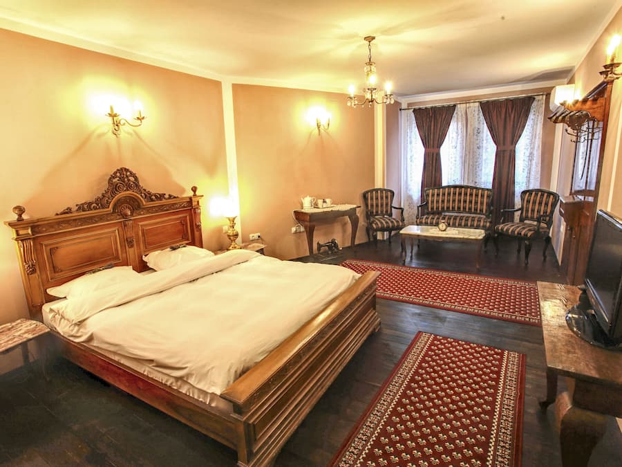 A hotel room with a large bed, a television, a desk, and a seating area with chairs.