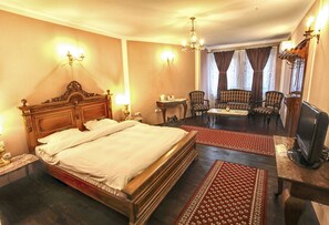 A hotel room with a large bed, a television, a desk, and a seating area with chairs. - Hotel Evmolpia (Plovdiv)