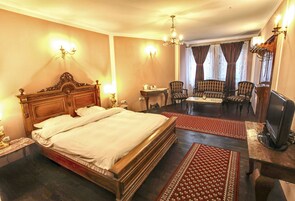 Habitación de hotel con una cama grande, televisión, escritorio y una zona de estar con sillas.