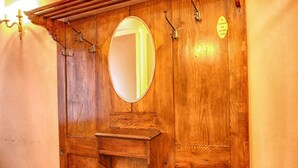 A wooden wardrobe with a mirror and hooks.