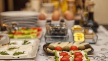 Una mesa de buffet con diversos alimentos, incluyendo brochetas de tomate y pepino, platos de carne en rodajas, y una variedad de otros platillos.