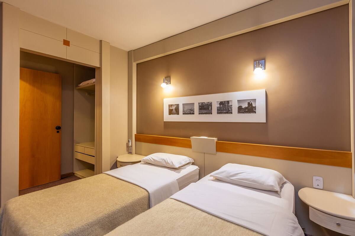 Ein Hotelzimmer mit zwei Betten, einer Holztür, einem Wandbild und einem Nachttisch.