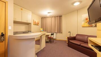 A compact living space with a kitchenette, a sofa, a TV, and a dining area.