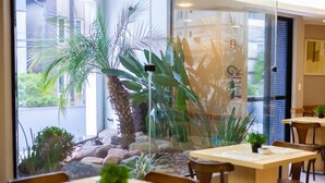A restaurant with indoor plants, wooden tables, and chairs.