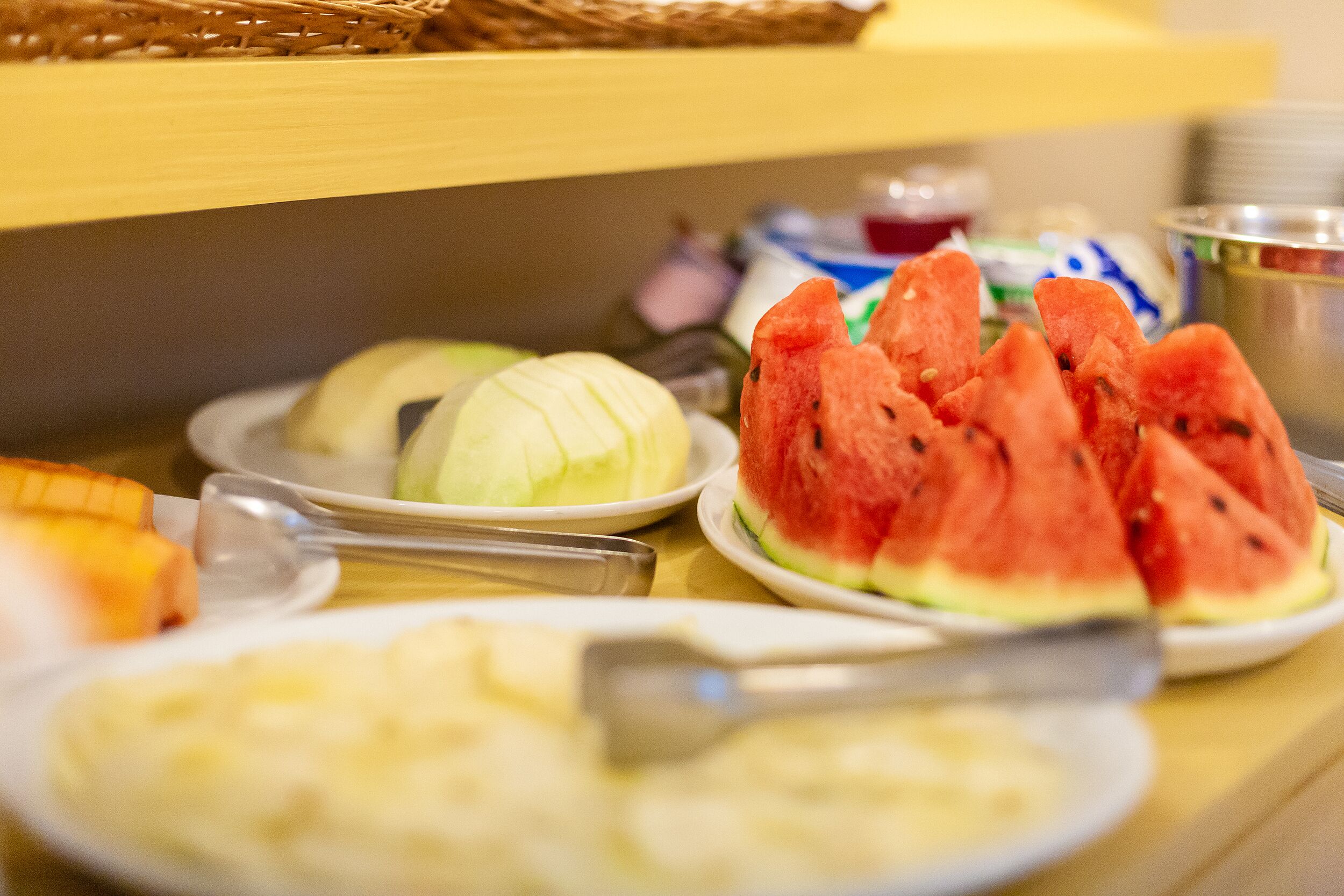 Ein Buffet mit verschiedenen Speisen, darunter Wassermelone, Kohl und weitere Gerichte.