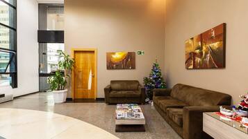 Een hal met een receptiebalie, twee banken, een salontafel met tijdschriften, een kerstboom en kunstwerken aan de wanden.
