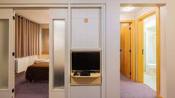 A hotel room with a bed, a TV, and a bathroom visible through an open door.