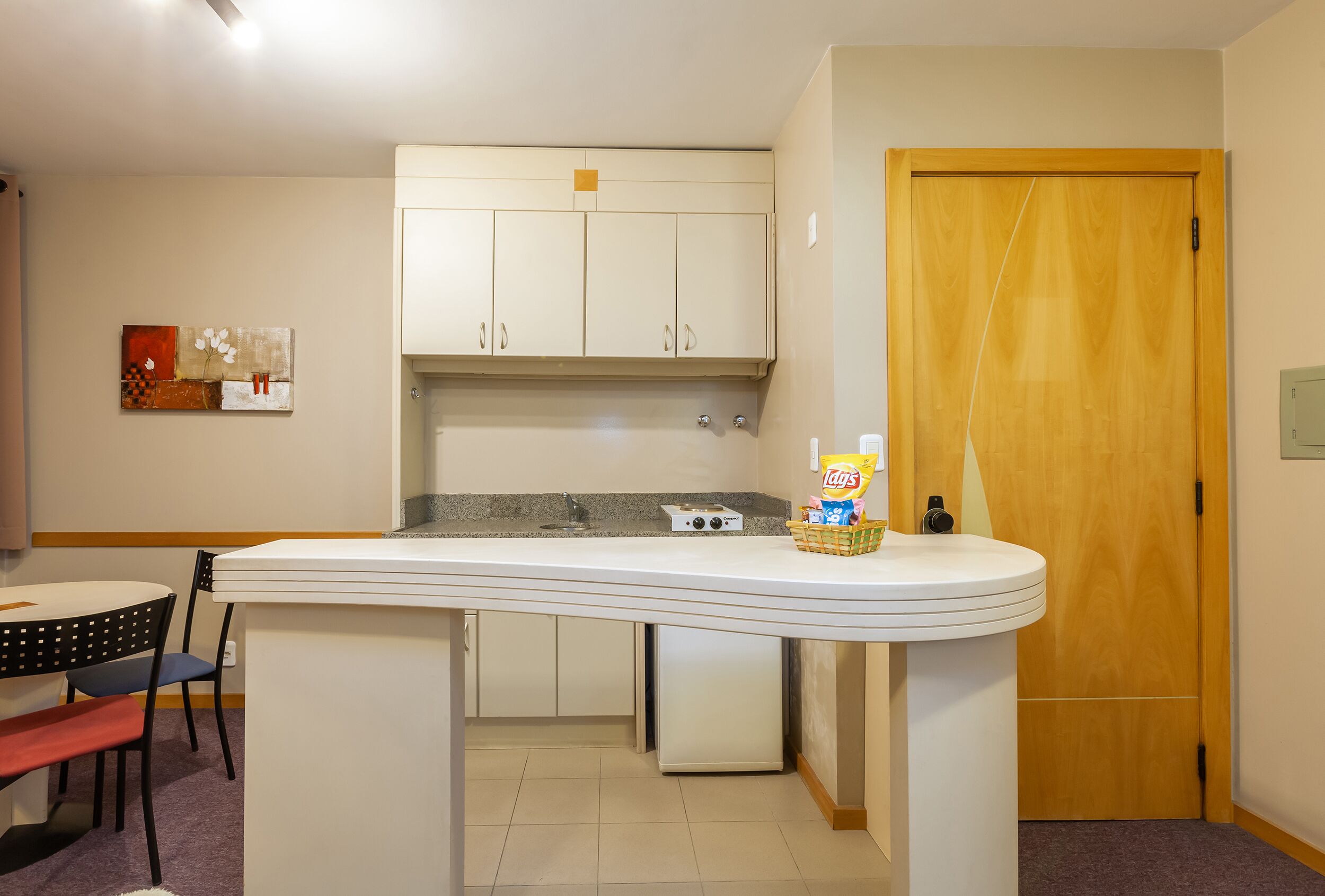 A compact kitchen with a white countertop, a built-in oven, and a wooden door.