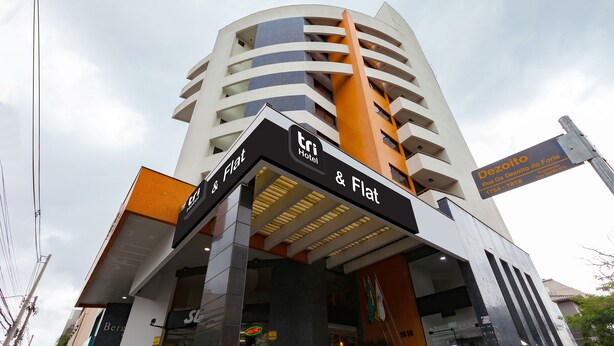 A hotel named 'Tri Hotel & Flat' with a modern design, featuring a prominent entrance and signage.