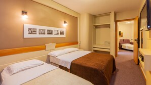 A hotel room with two beds, a wardrobe, a mirror, and a wall-mounted picture frame.
