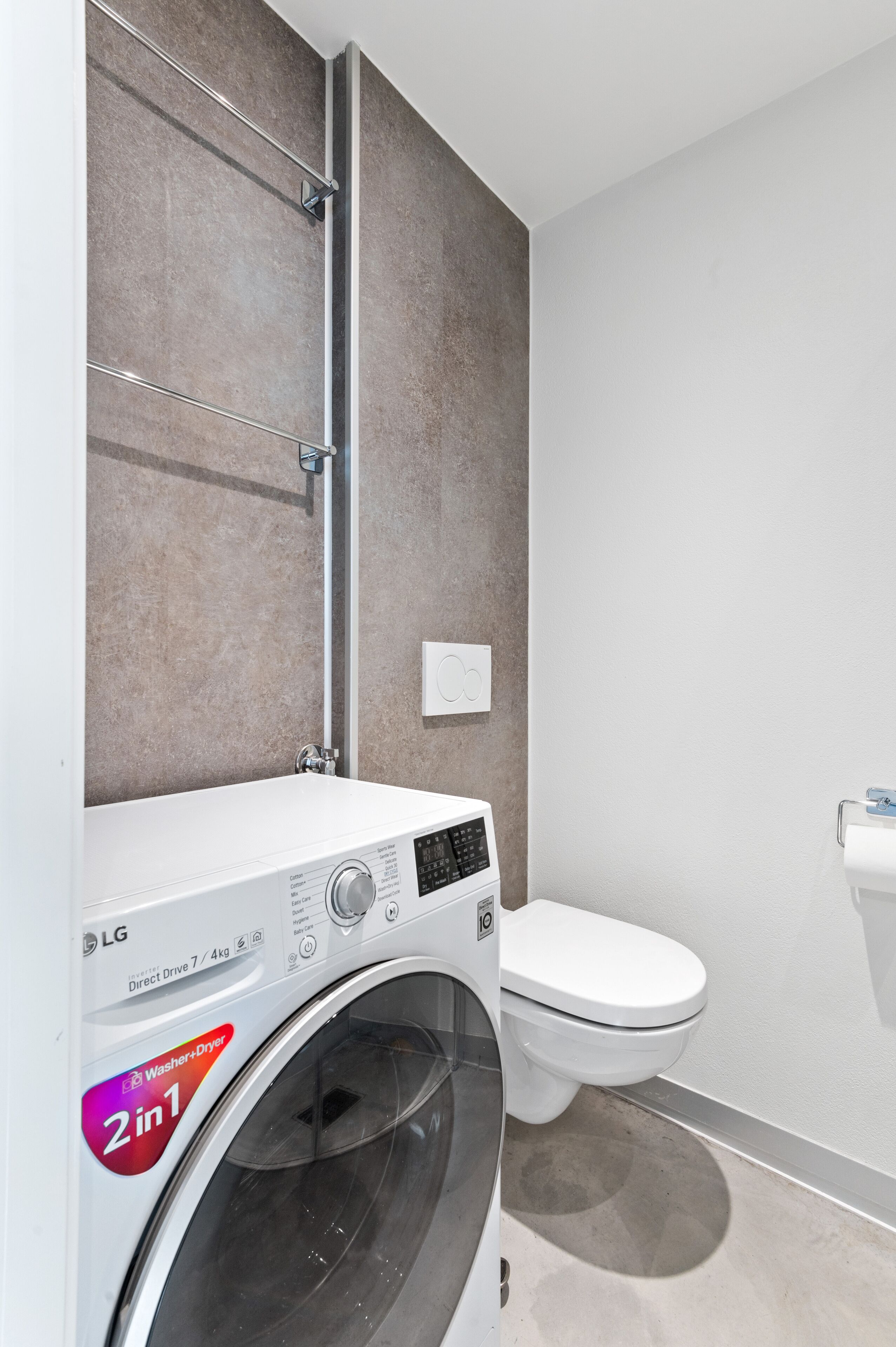 Ein kleines Badezimmer mit Waschmaschine, Toilette und Handtuchhalter.