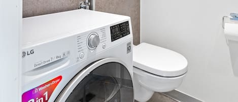 Ein kleines Badezimmer mit Waschmaschine, Toilette und Handtuchhalter.