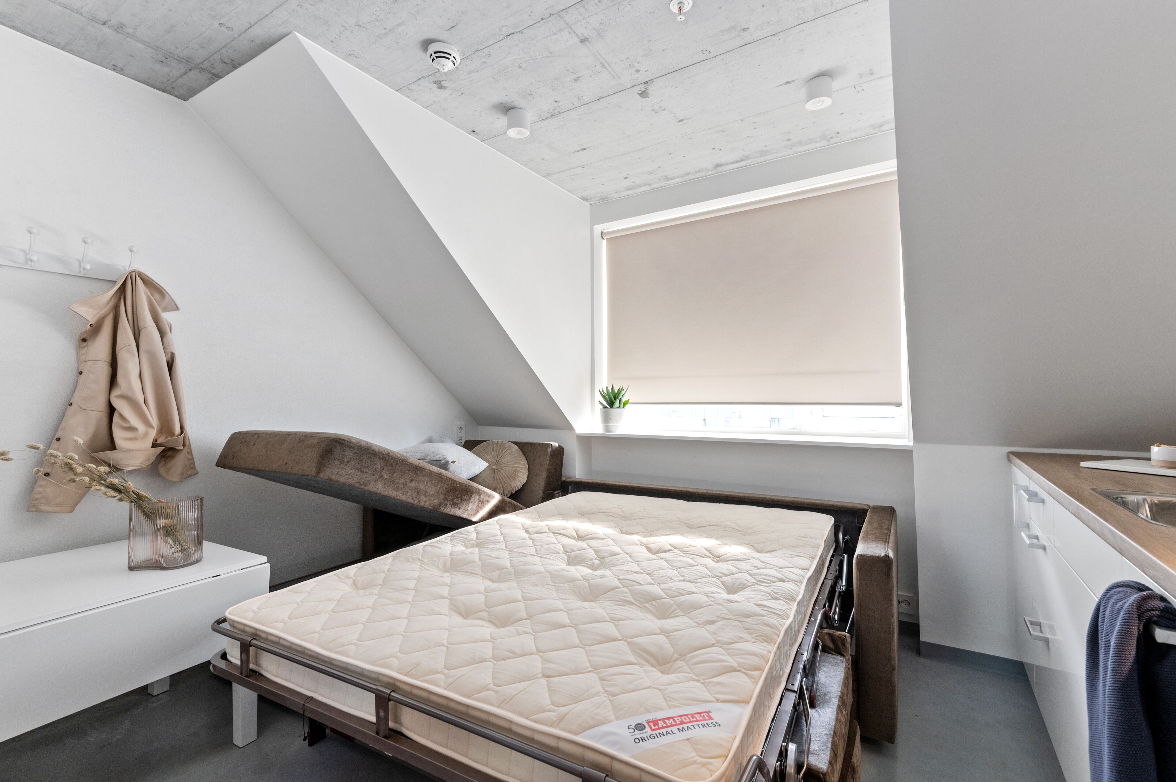 Quarto moderno com beliche, mesinha de cabeceira, janela com vista e parede branca.