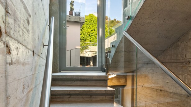 A modern staircase with glass railings and a view of greenery outside. - Aalesund City Apartment (Ålesund)