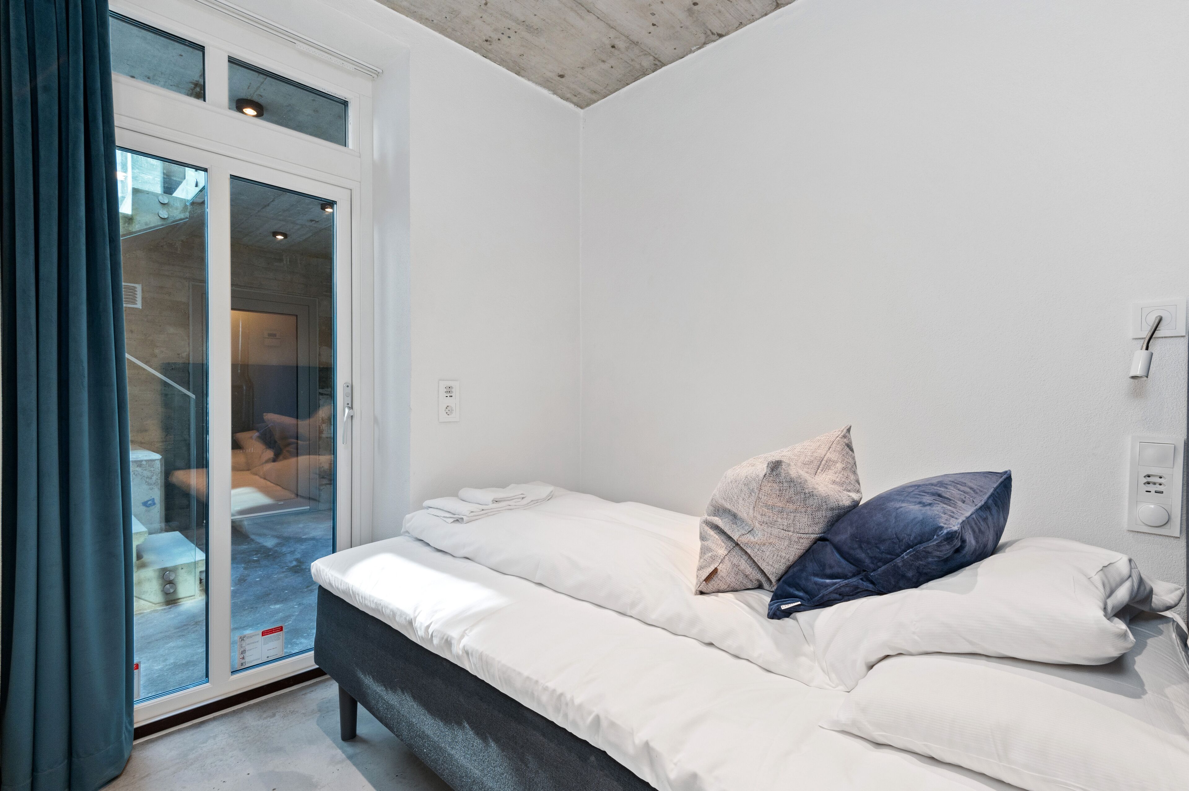 Un dormitorio con cama, almohadas, una ventana y una puerta.