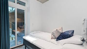 A bedroom with a bed, pillows, a window, and a door.