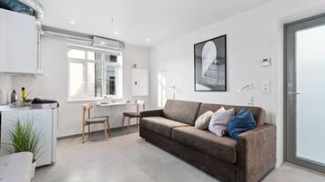 A modern, well-lit room with a brown sofa, a desk, and a chair.