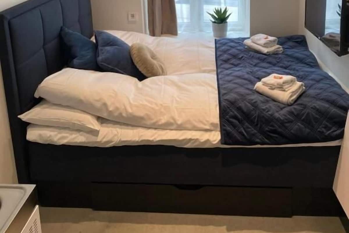 Une chambre d’hôtel avec un grand lit, un téléviseur fixé au mur et une fenêtre avec des rideaux.