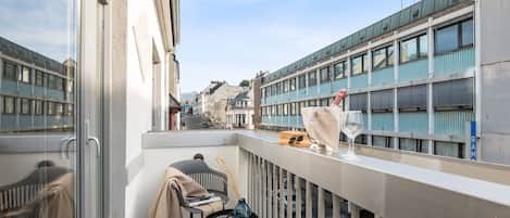 A balcony with a chair, a small table, and a glass of wine.