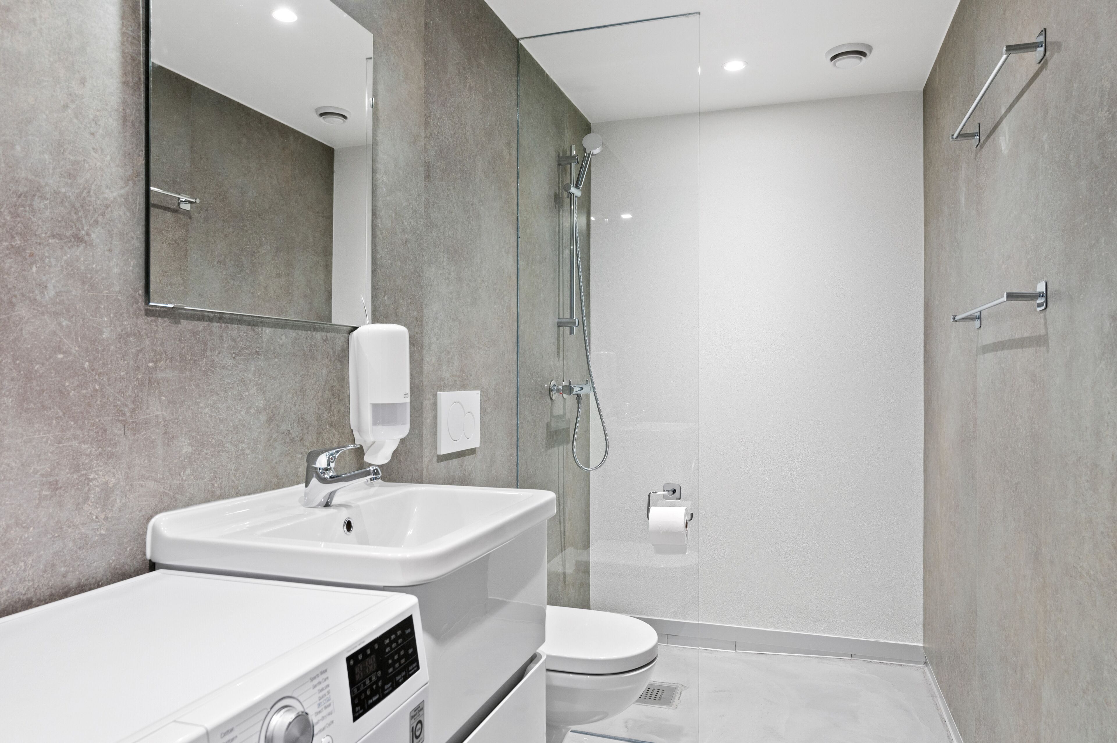 A modern bathroom with a glass-enclosed shower, a white sink, and a toilet.