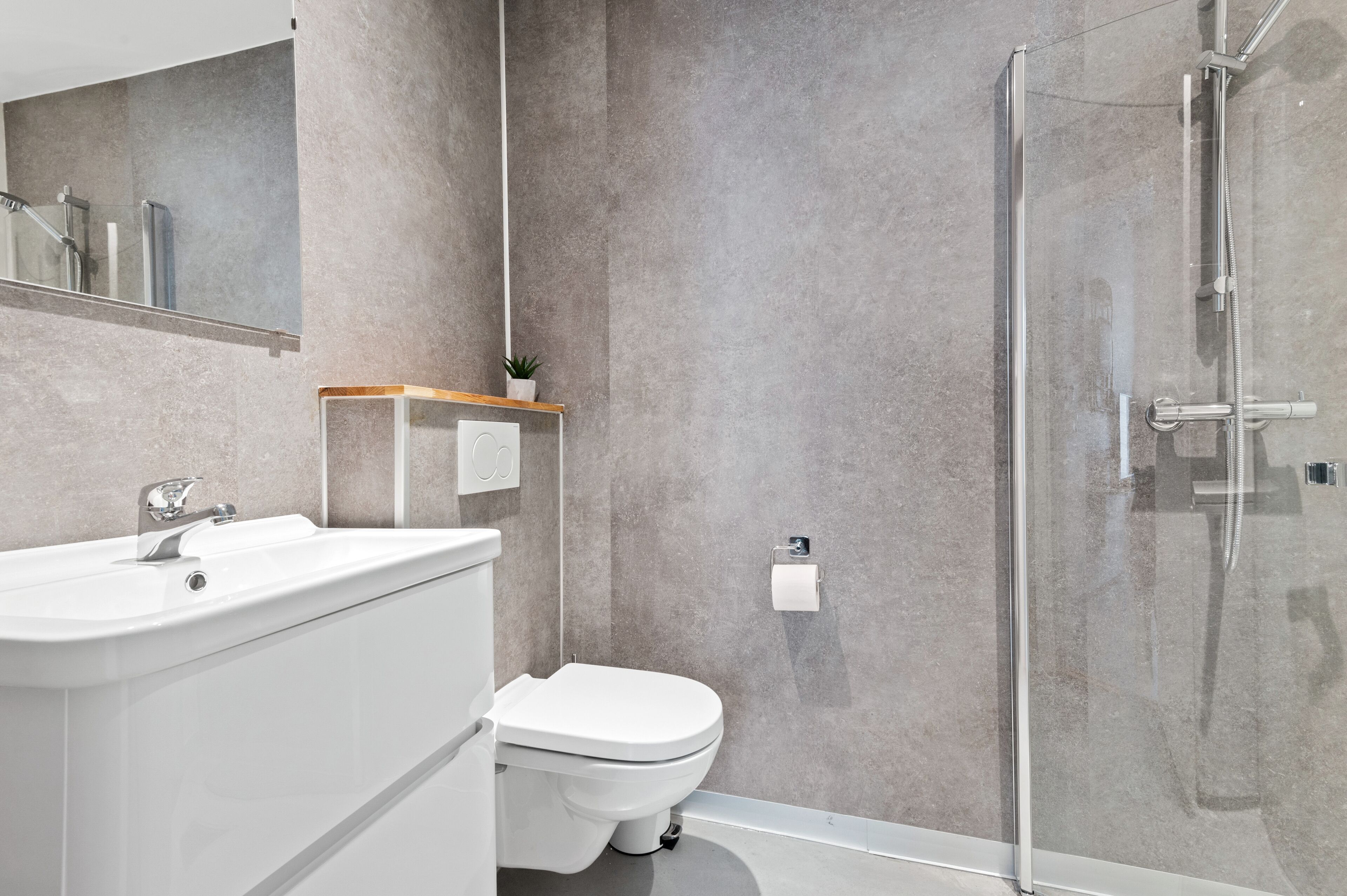 A modern bathroom with a glass shower enclosure, a white sink, and a toilet.