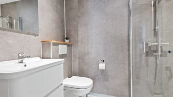 A modern bathroom with a glass shower enclosure, a white sink, and a toilet.