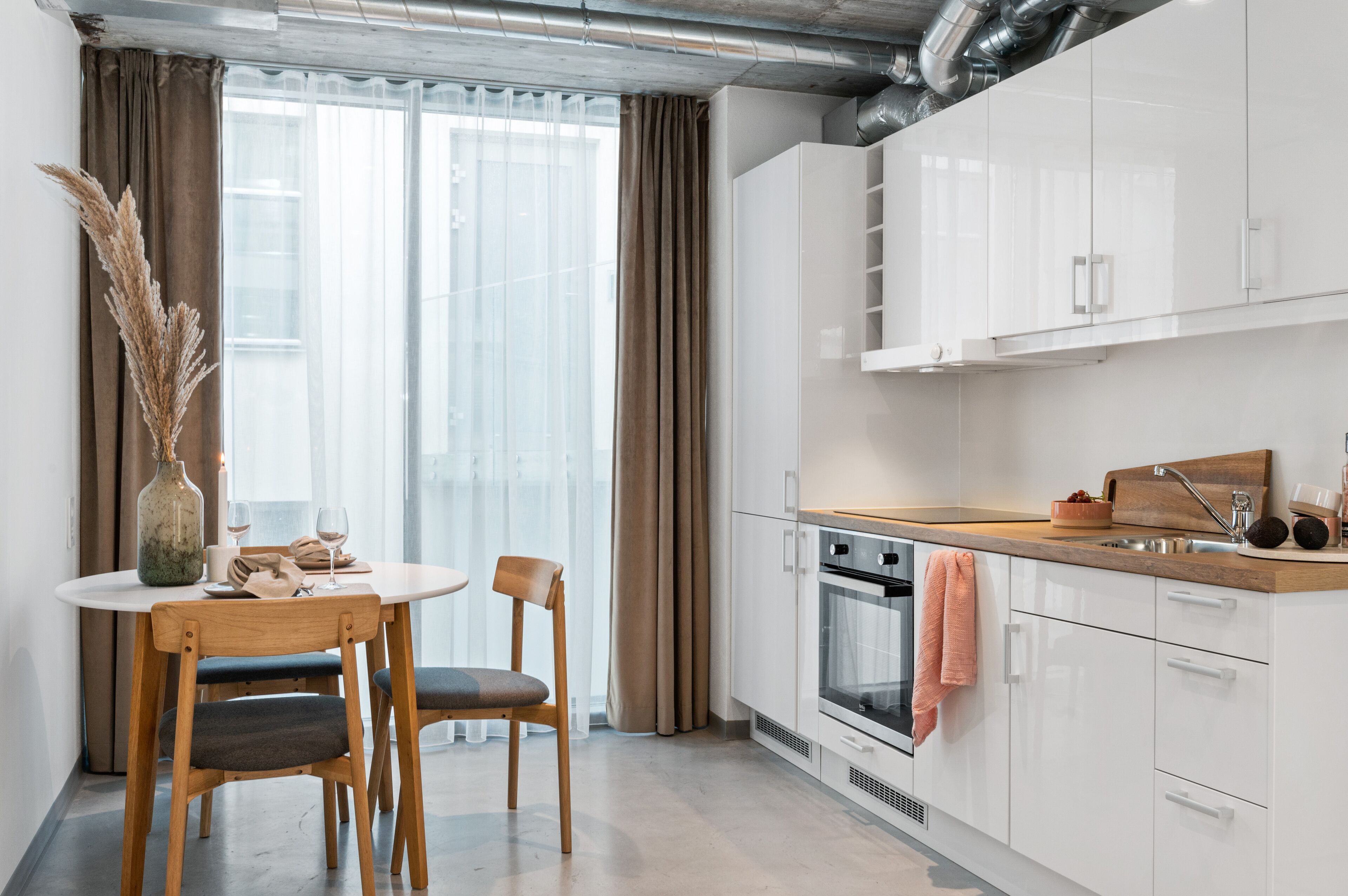 A modern kitchen with white cabinets, a wooden countertop, and a built-in oven.