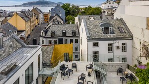 A rooftop terrace with outdoor seating, a view of the city, and a yellow awning. - Aalesund City Apartment (Ålesund)