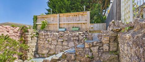 A stone wall with a wooden fence and potted plants.