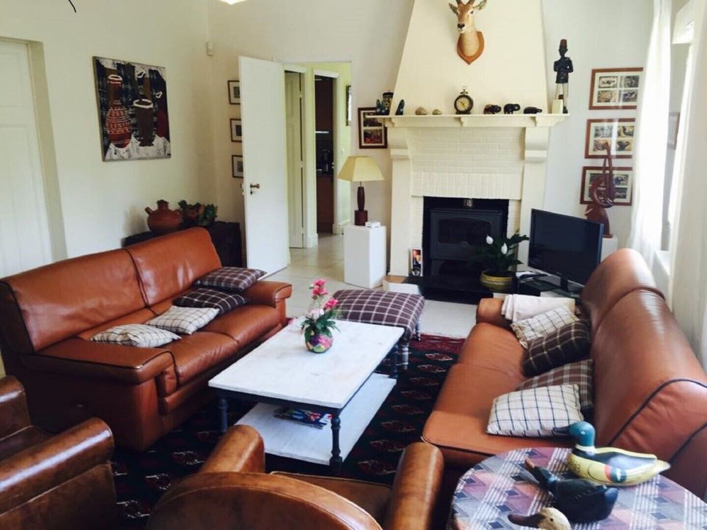 A living room with a fireplace, leather sofas, a coffee table, and a television.