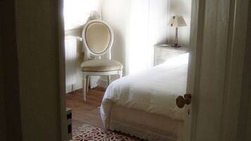 A bedroom with a bed, a chair, a nightstand, and a patterned rug.