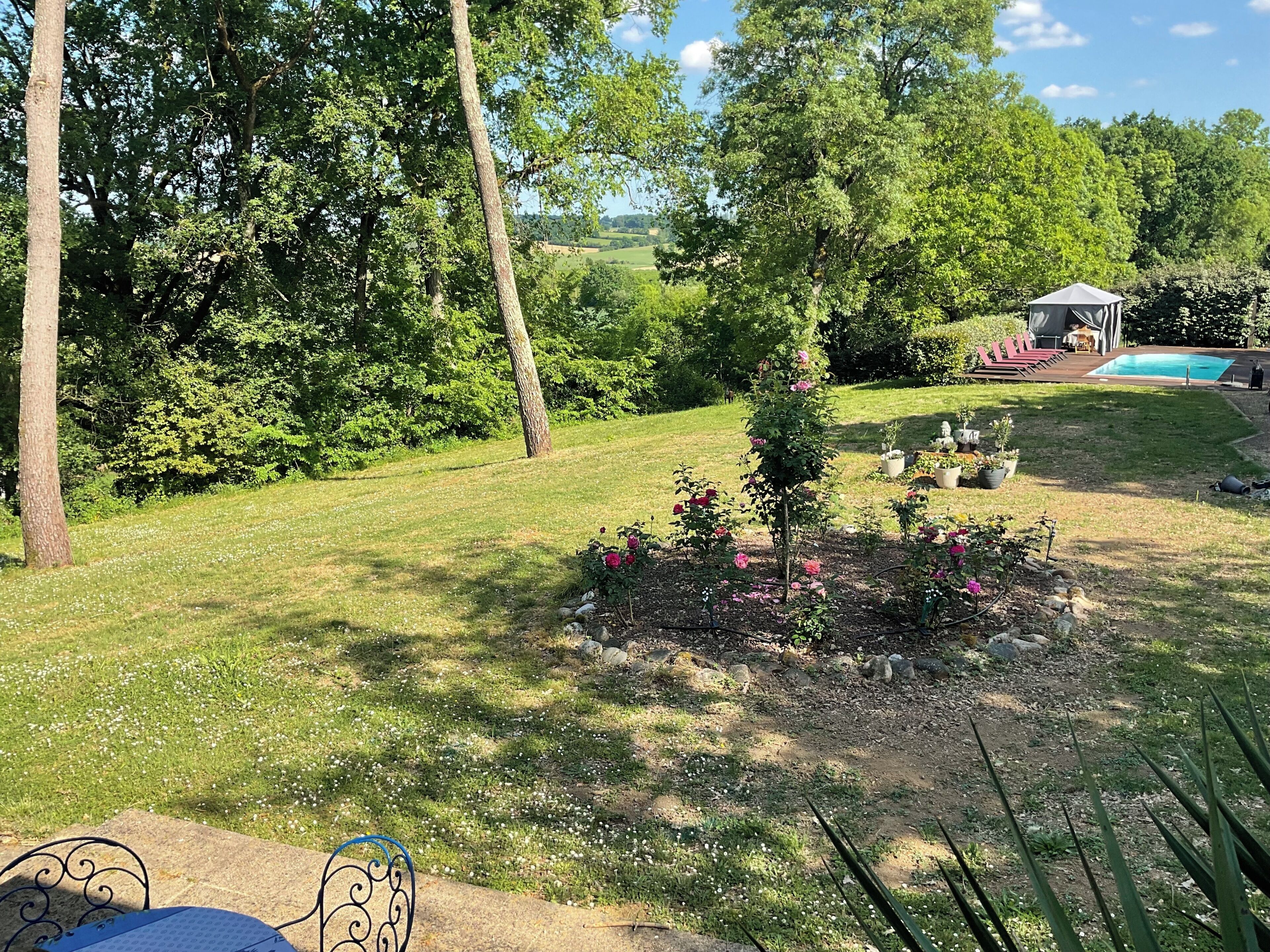 A backyard with a small garden, a swimming pool, and a covered seating area.