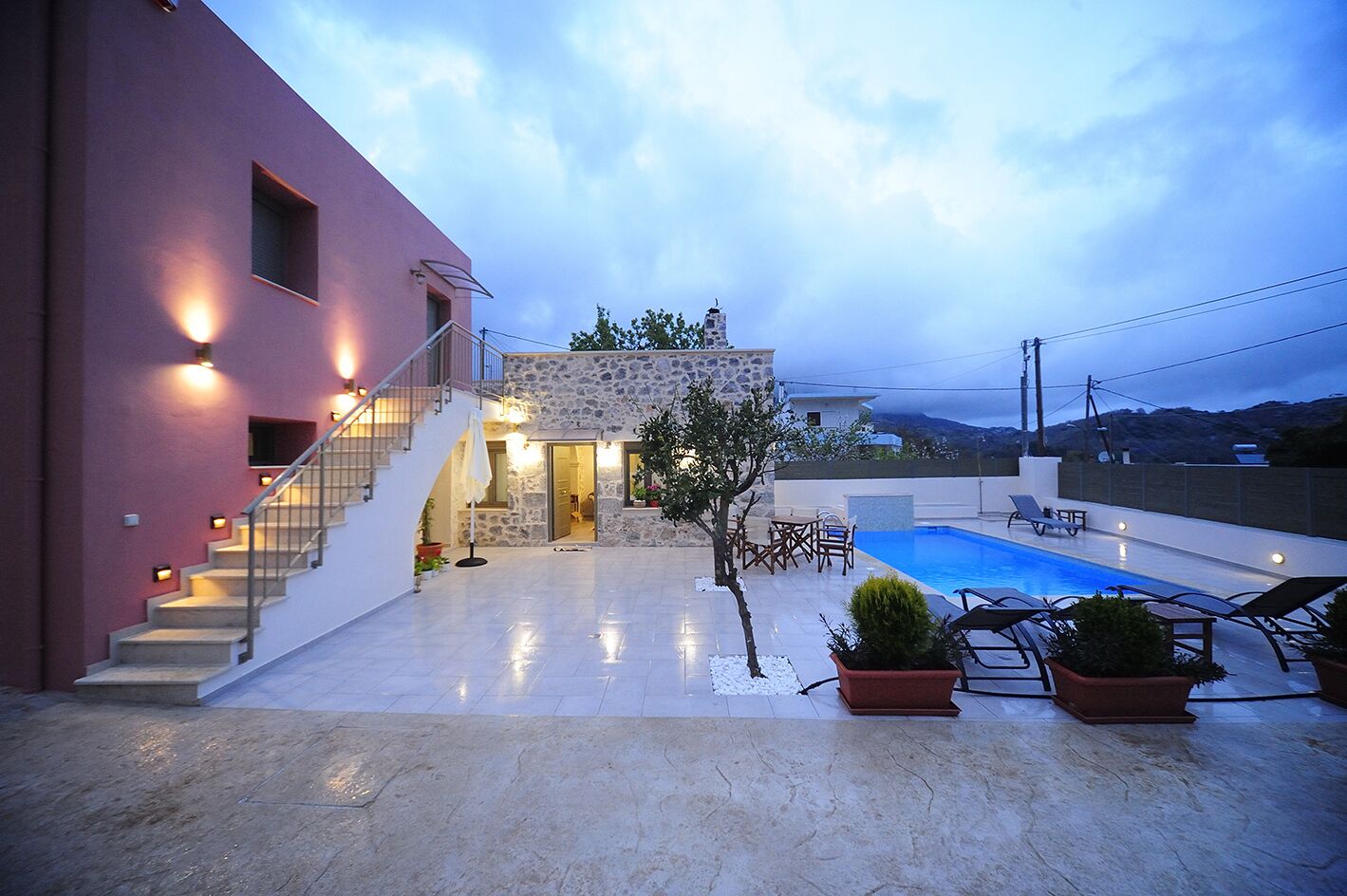 Une villa moderne avec une façade en pierre, une piscine et un escalier menant à l’étage supérieur.