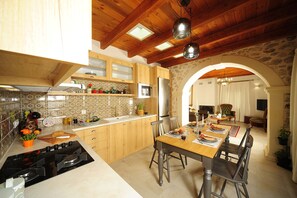 Cozinha moderna com armários de madeira, uma ilha central e área de refeições com mesa e cadeiras.