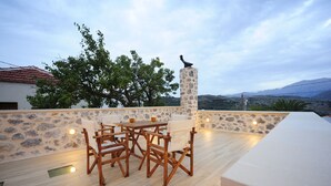 An outdoor patio with a stone wall, wooden chairs, a table, and a statue. - Hawk Villa, Timeless Village Escape with Pool (Gerakari, Rethymno)