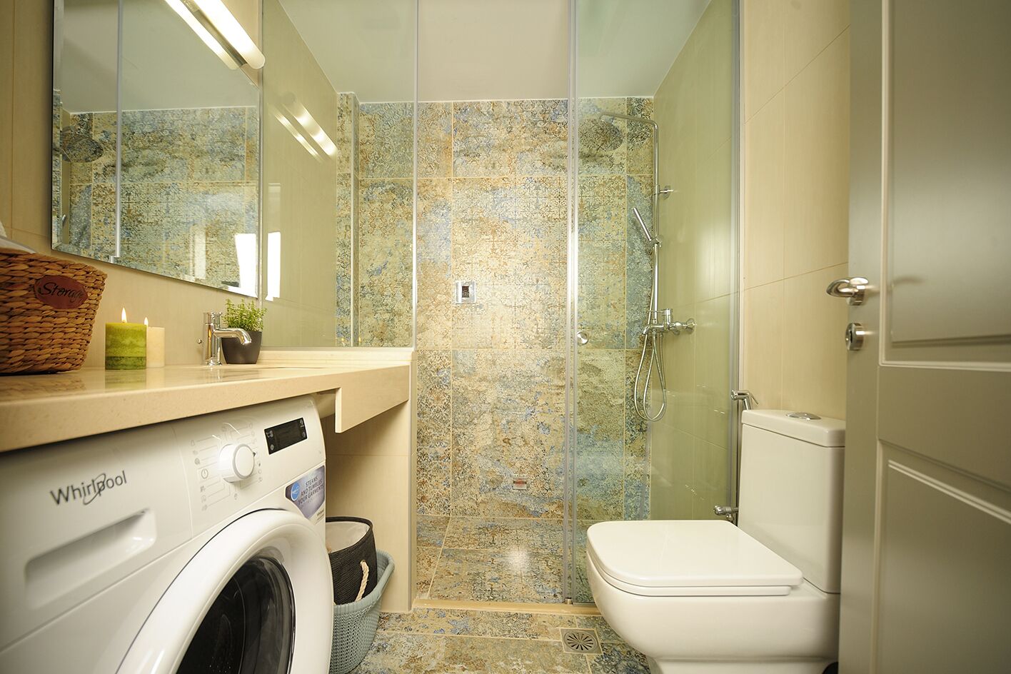 A modern bathroom with a Whirlpool washing machine, a glass shower enclosure, and a toilet.