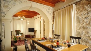 A dining area with a long wooden table set for four, surrounded by stone walls and wooden beams. - Hawk Villa, Timeless Village Escape with Pool (Gerakari, Rethymno)