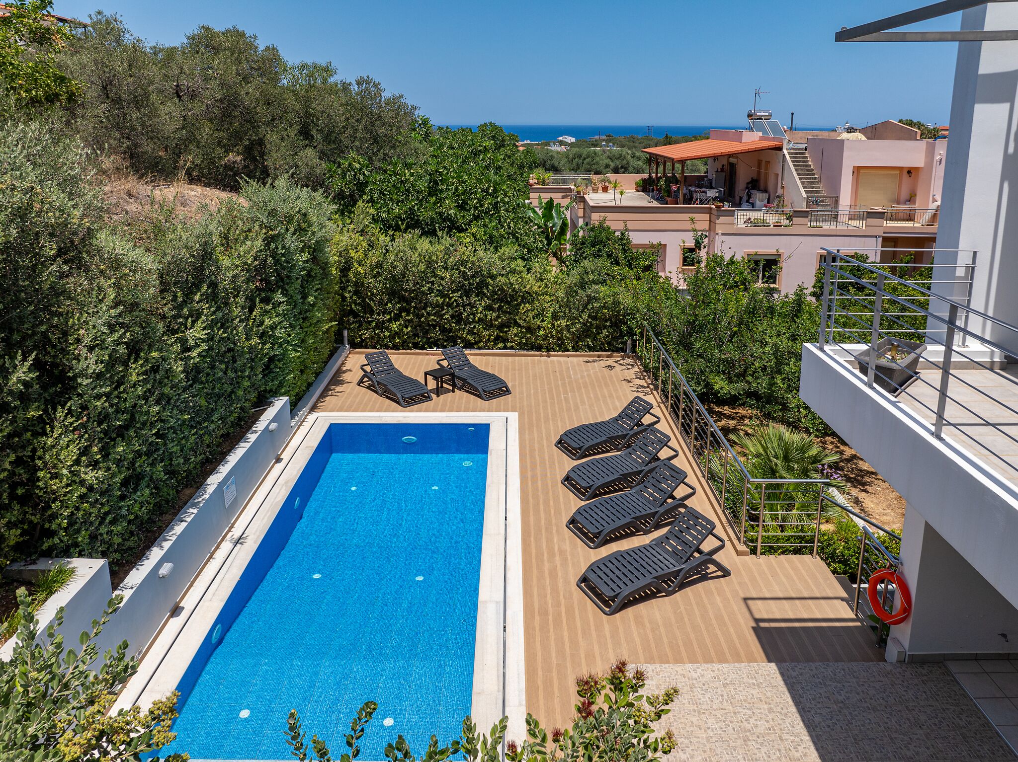 A rooftop pool with lounge chairs and a view of the sea.