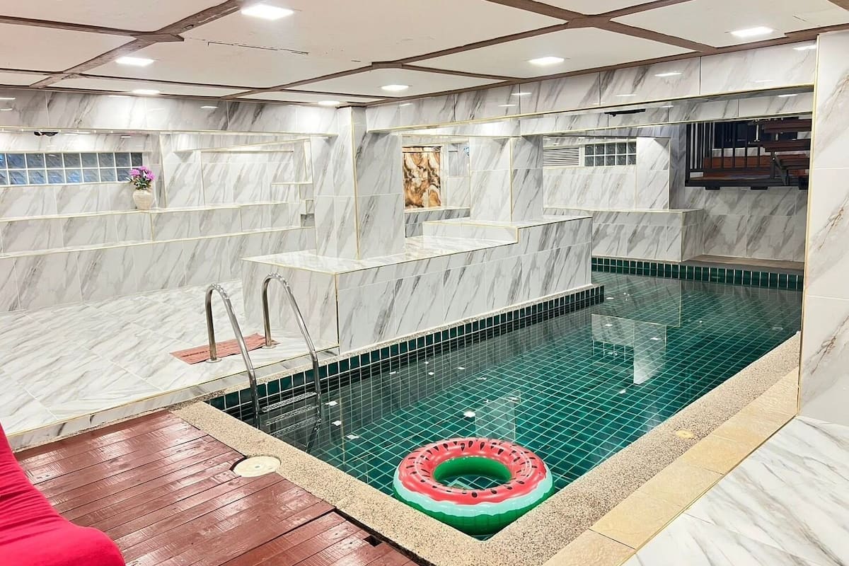 Una piscina con cubierta de madera y un flotador rojo.